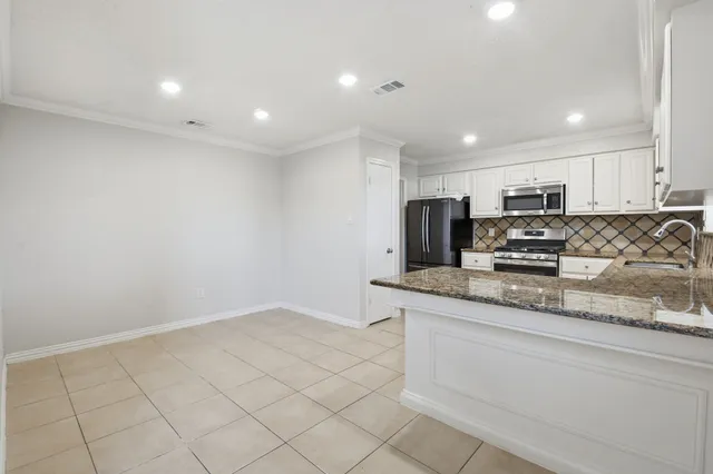 a kitchen with granite countertop white cabinets and stainless steel appliances