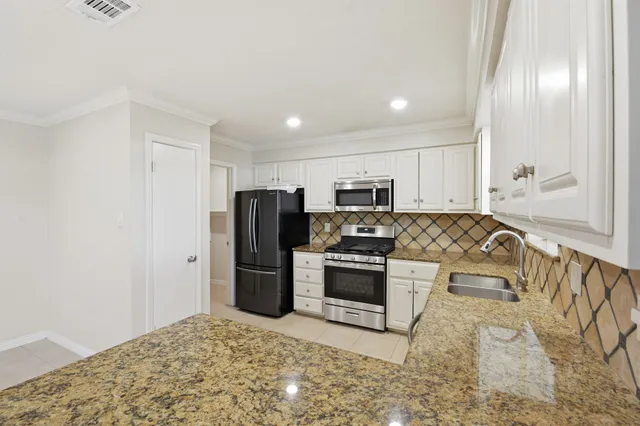 a kitchen with white cabinets and appliances