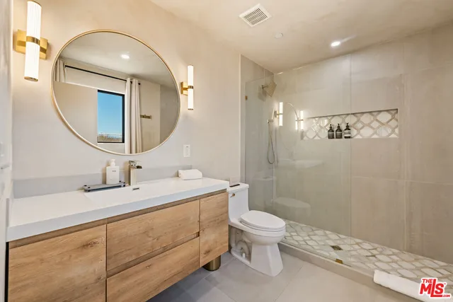a bathroom with a double vanity sink toilet mirror and shower