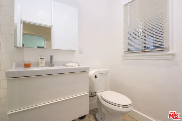 a bathroom with a toilet sink vanity and mirror