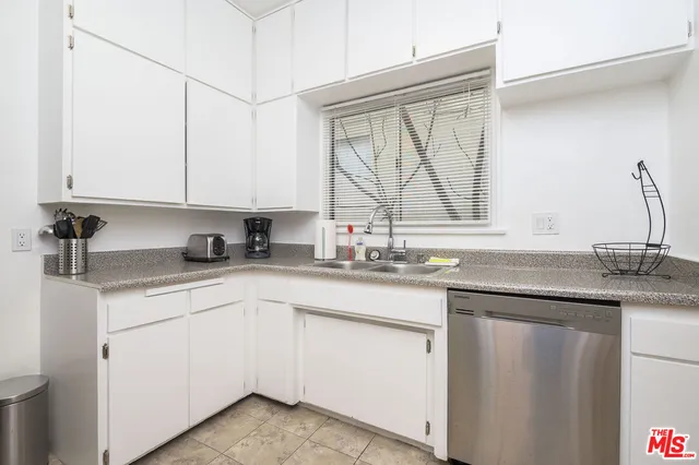a kitchen with white cabinets sink and window