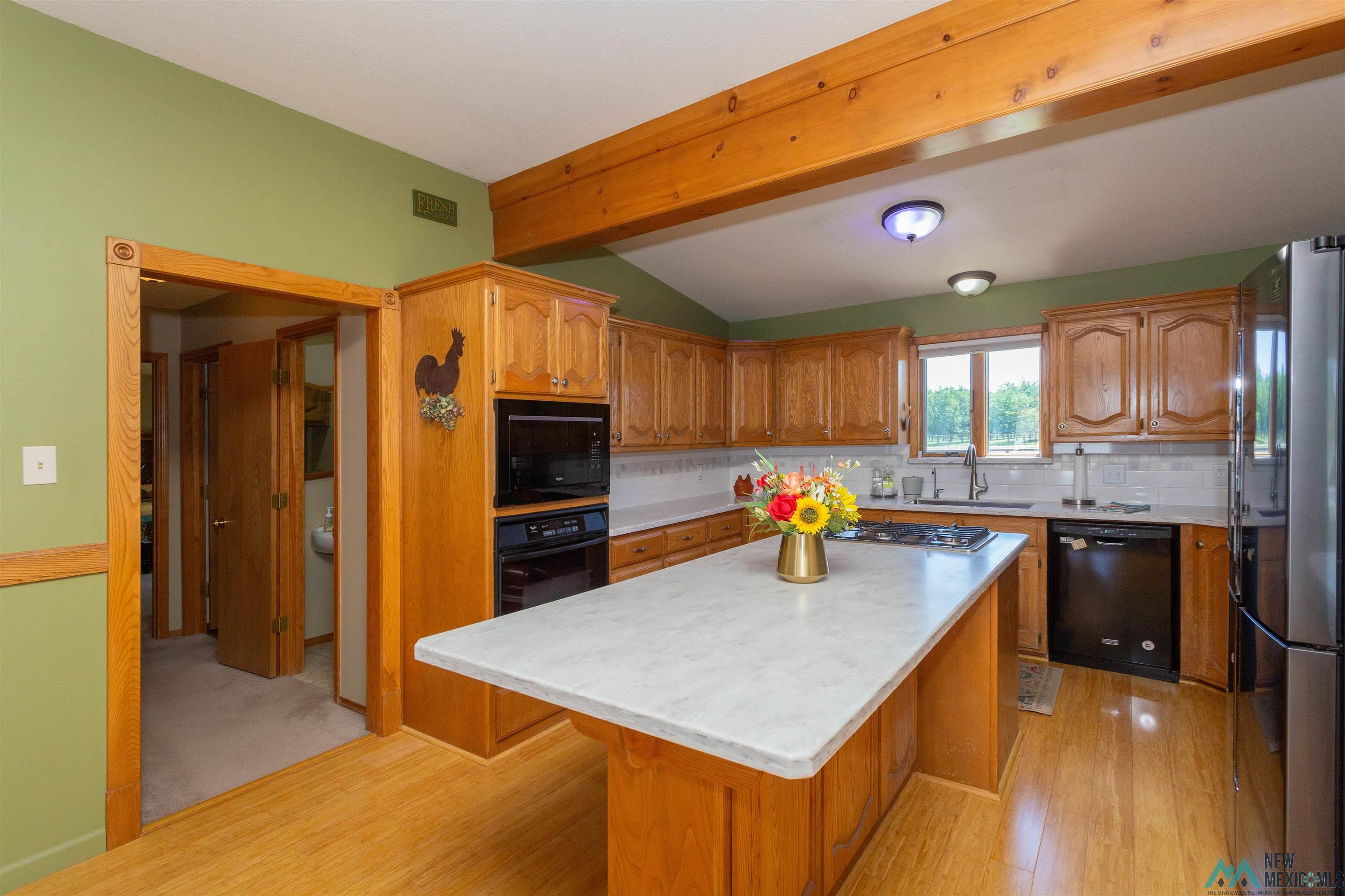 2012 South Haldeman Road Artesia, NM 88210 - Photo 20 of 96 Kitchen featuring wood-finish flooring, a central island with a light-toned countertop, wood cabinetry, built-in appliances, and a window above the sink