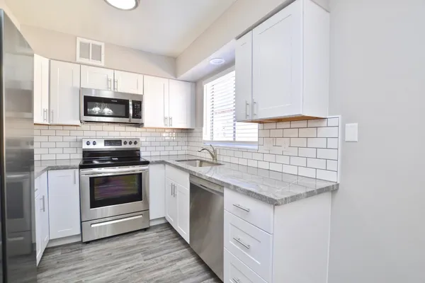 a kitchen with granite countertop a stove a sink and a microwave