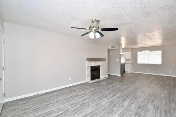 an empty room with wooden floor fan and windows