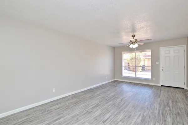 a view of an empty room with wooden floor and a window