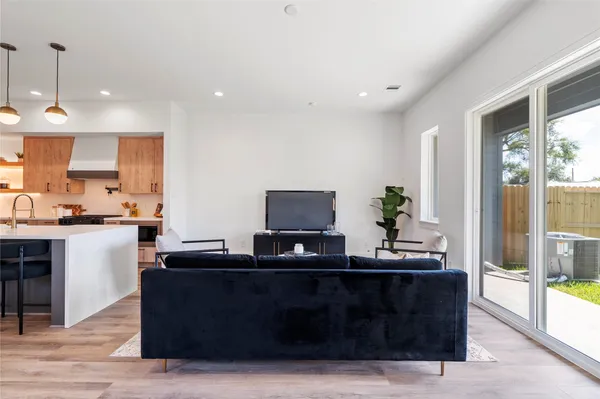 a living room with stainless steel appliances kitchen island granite countertop a sink and a wooden floor