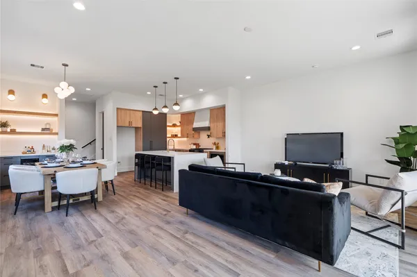 a living room with furniture a flat screen tv and kitchen view