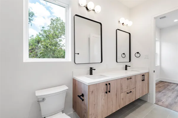 a bathroom with double vanity sink a mirror and a toilet