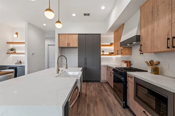 a kitchen with stainless steel appliances granite countertop a stove a sink dishwasher and a refrigerator with wooden floor