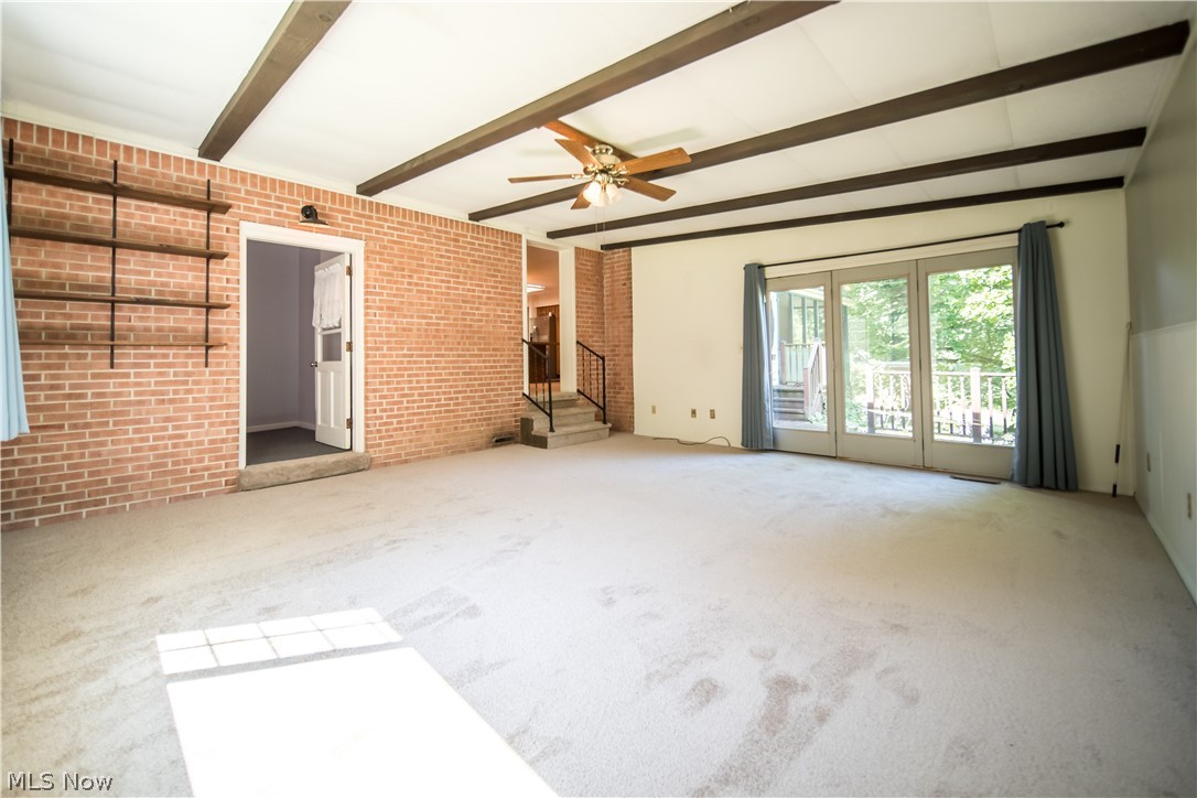 11063 Diagonal Road Mantua, OH 44255 - Photo 11 of 40 Unfurnished living room with brick wall, ceiling fan, carpet flooring, and beam ceiling
