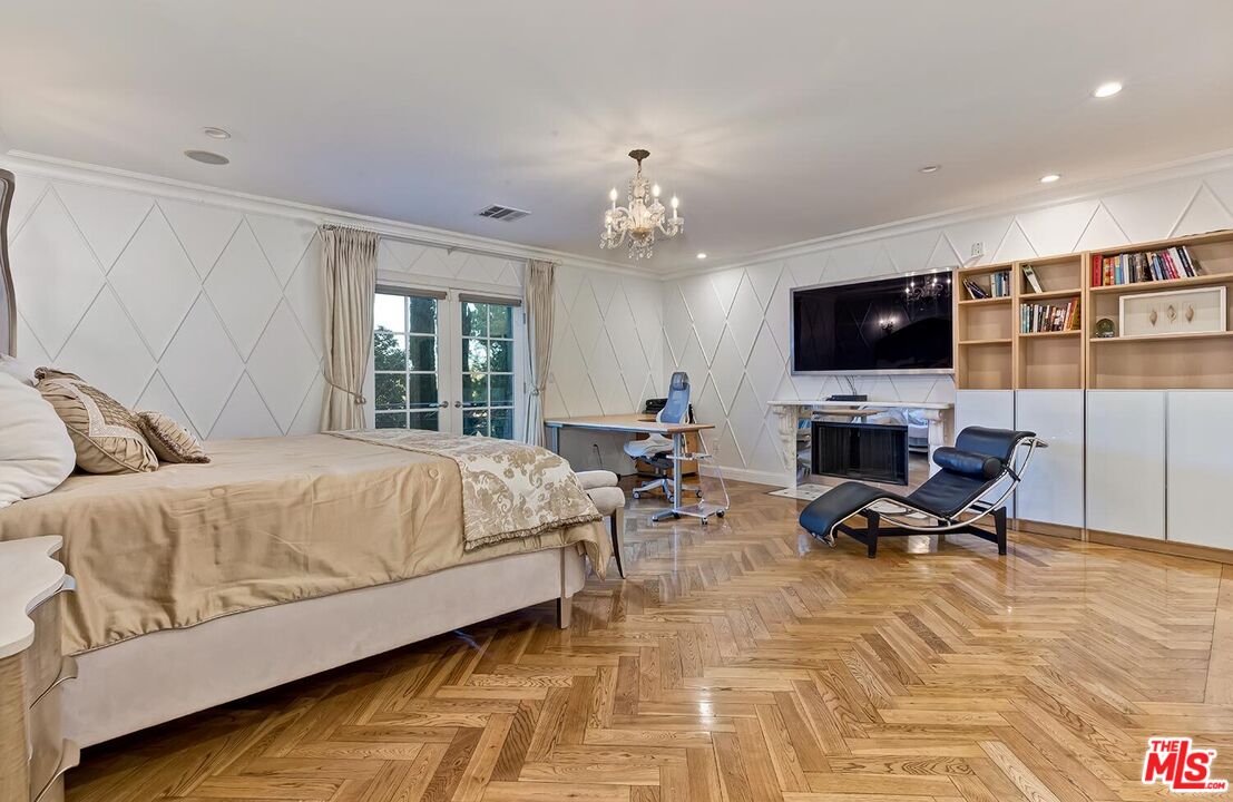 725 North Faring Road Los Angeles, CA 90077 - Photo 43 of 56 a spacious bedroom with a bed a chair and a flat screen tv