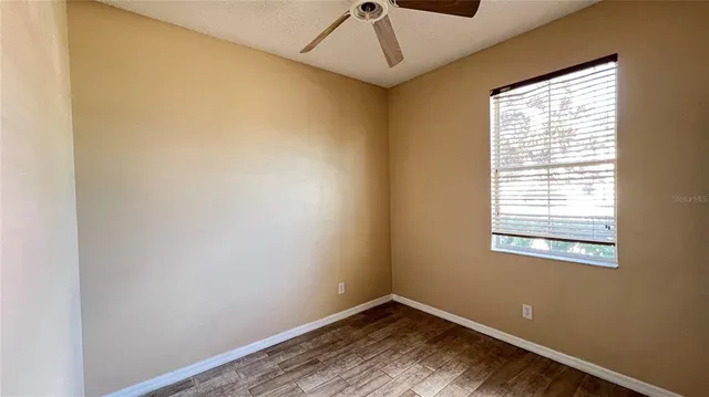 a view of an empty room with a window and wooden floor