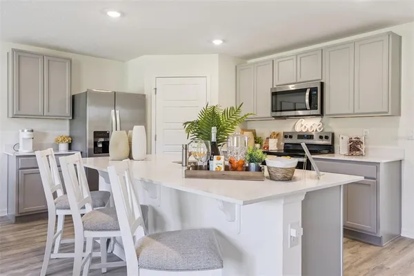 a kitchen with stainless steel appliances a sink a microwave a refrigerator and cabinets