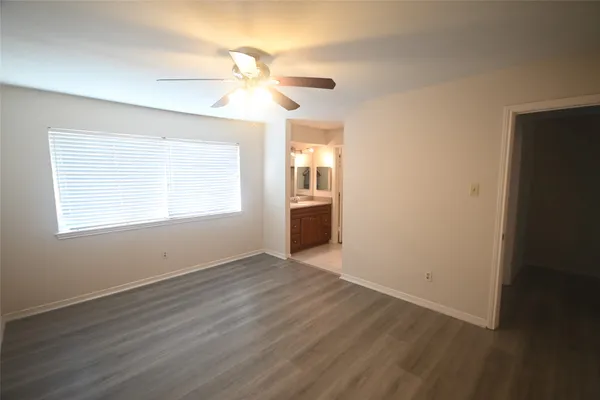 an empty room with wooden floor chandelier fan and windows