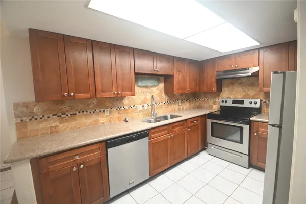 a kitchen with granite countertop stainless steel appliances a sink stove and cabinets