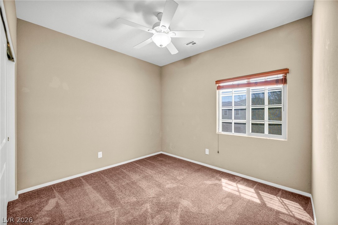 5014 Fiery Sky Ridge Street Las Vegas, NV 89148 - Photo 11 of 21 A well-lit bedroom featuring a ceiling fan and plush carpeting, ready for personalization.