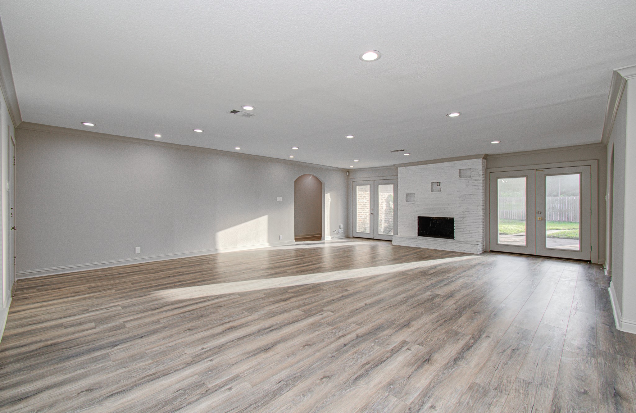 1801 Benbow Way Houston, TX 77080 - Photo 7 of 32 This spacious living room features elegant wood flooring, a modern white fireplace, recessed lighting, and large glass doors leading to a patio, offering abundant natural light.