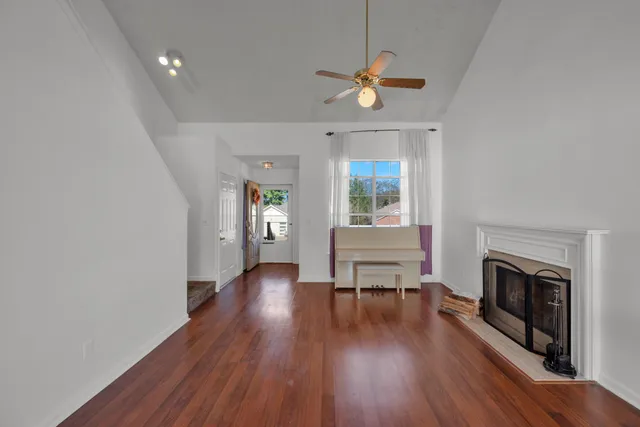 an empty room with wooden floor a fireplace and windows