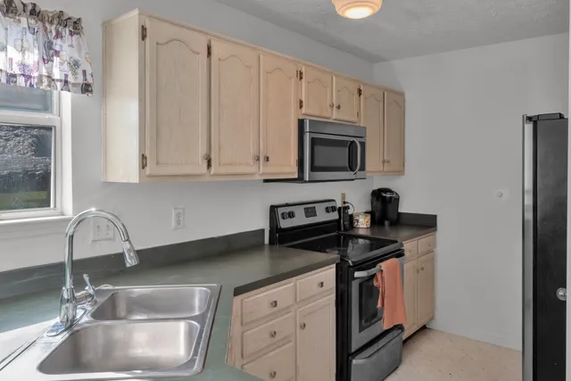 a kitchen with granite countertop a sink stove and microwave