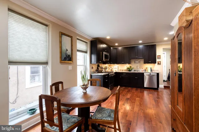 a kitchen with stainless steel appliances kitchen island granite countertop a sink a stove a kitchen island with chairs and wooden floor