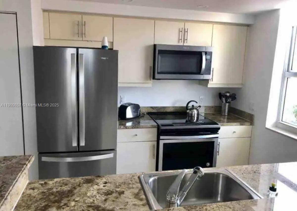 2889 McFarlane Road, Unit 1001 Miami, FL 33133 - Photo 9 of 35 a kitchen with a stove and a refrigerator