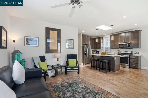 a living room with furniture kitchen view and a wooden floor