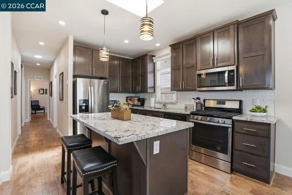 a kitchen with kitchen island granite countertop wooden cabinets and stainless steel appliances