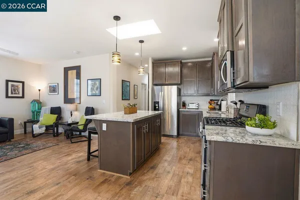 a kitchen with kitchen island granite countertop a sink a counter top space appliances and cabinets