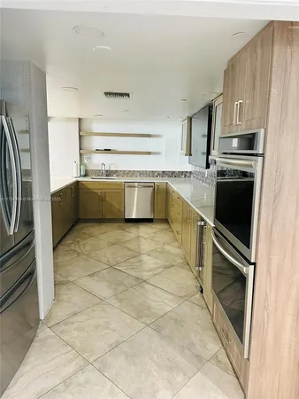 a kitchen with granite countertop a refrigerator and a stove top oven