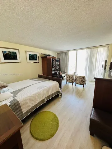 a spacious bedroom with a bed a couch and a potted plant on the dresser