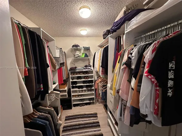 a view of walk in closet with clothes and shoes