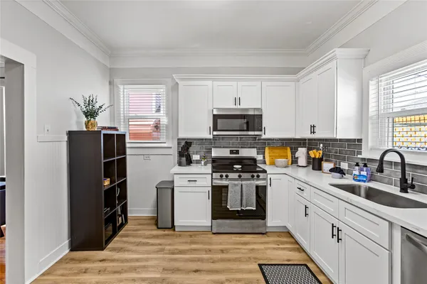 a kitchen with stainless steel appliances granite countertop a stove top oven a sink dishwasher and a refrigerator with wooden floor