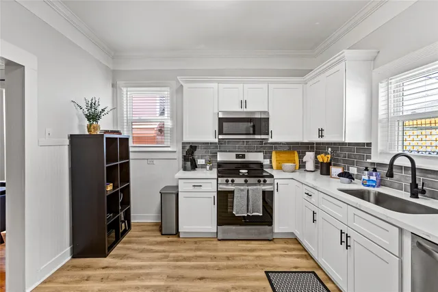 a kitchen with stainless steel appliances granite countertop a stove top oven a sink dishwasher and a refrigerator with wooden floor