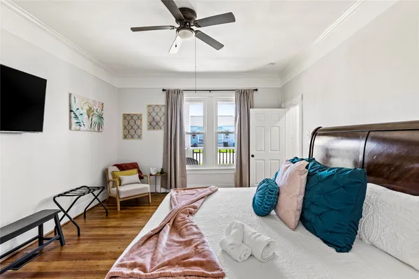 a bedroom with a bed a couch and a flat tv screen on the dresser
