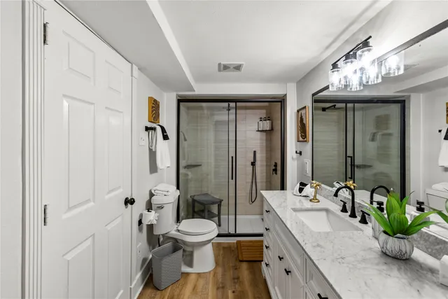 a spacious bathroom with a granite countertop sink a toilet and a large mirror