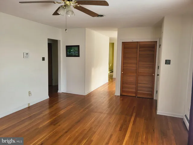 an empty room with wooden floor closet and windows
