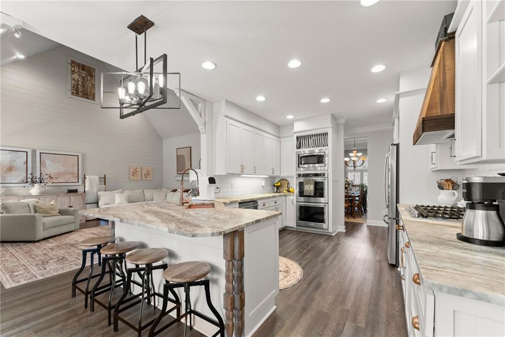 2195 East Maddox Road Buford, GA 30519 - Photo 12 of 100 a kitchen with stainless steel appliances granite countertop a sink dishwasher a stove a dining table and chairs with wooden floor