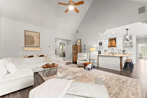 a kitchen with stainless steel appliances granite countertop a stove a sink dishwasher a refrigerator and white cabinets with wooden floor