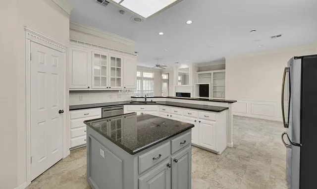 a kitchen with kitchen island a sink stainless steel appliances and white cabinets