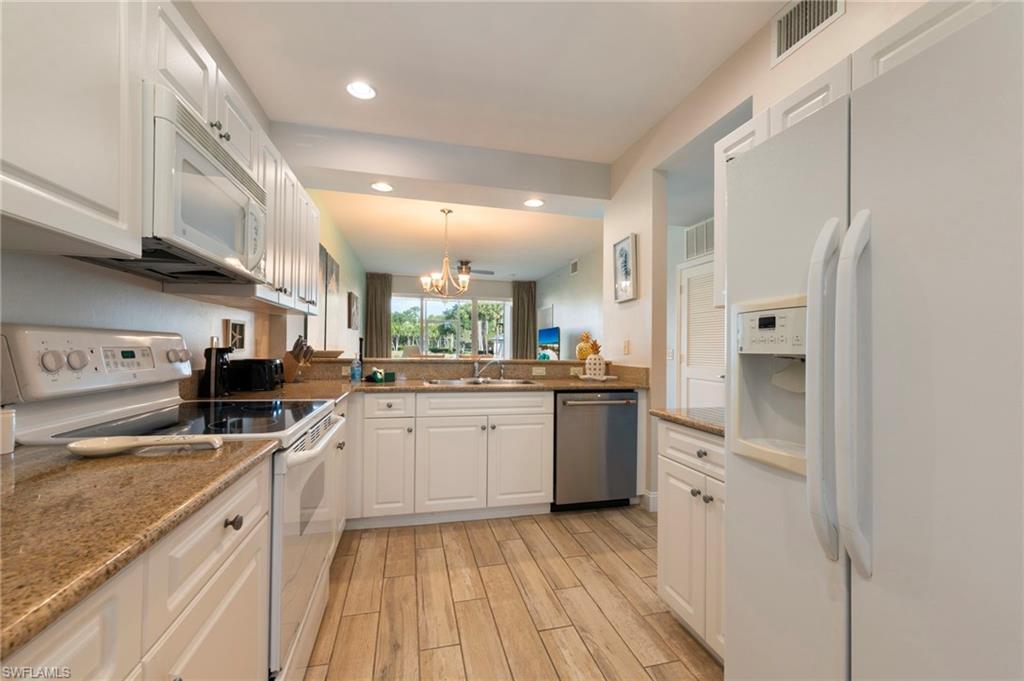7940 Mahogany Run Lane, Unit 612 Naples, FL 34113 - Photo 14 of 25 a large kitchen with stainless steel appliances granite countertop a lot of counter space and wooden floors
