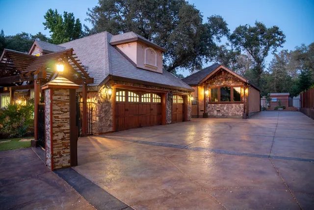 a view of a white house with a big yard plants and large trees