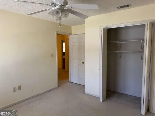 an empty room with a ceiling fan and closet area