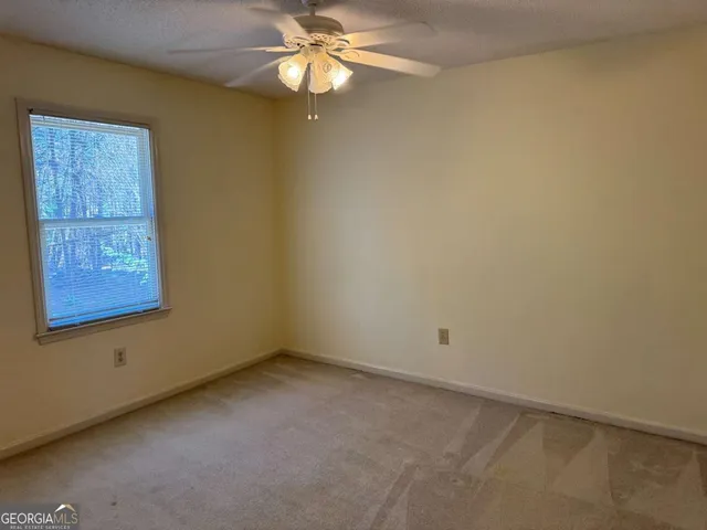 an empty room with a window and a fan