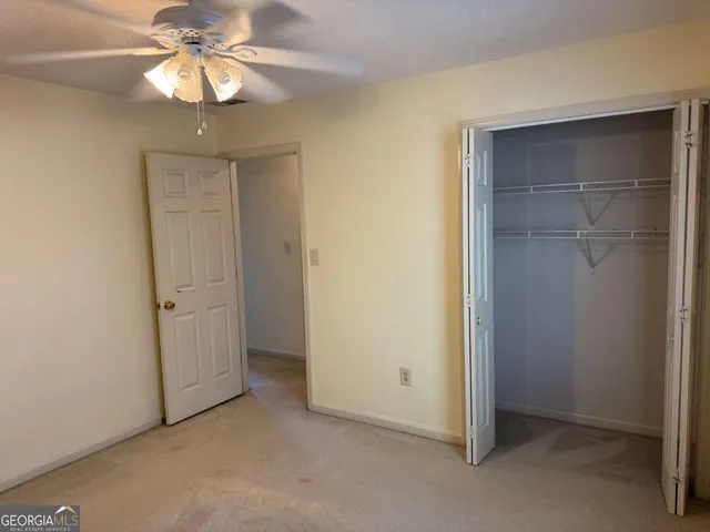 a view of an empty room with a chandelier fan