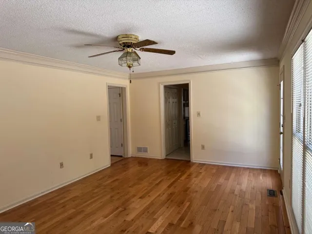 a view of an empty room with wooden floor and a window