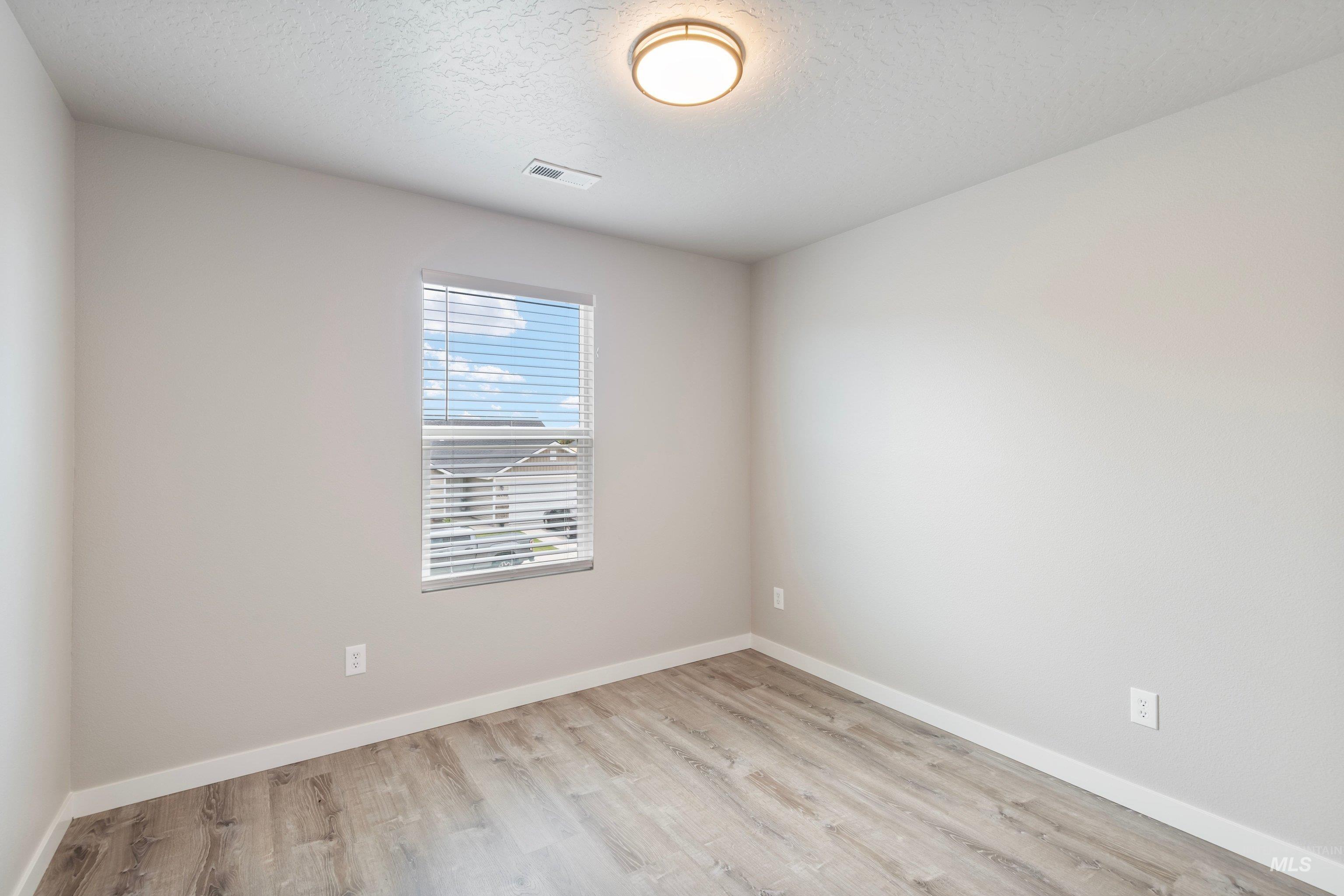 16759 Abram Avenue Caldwell, ID 83607 - Photo 14 of 33 Neutral-toned room featuring a single window with horizontal blinds, wood-finish flooring, and white trim