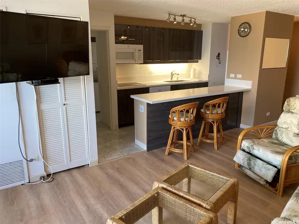 a living room with stainless steel appliances furniture and a flat screen tv