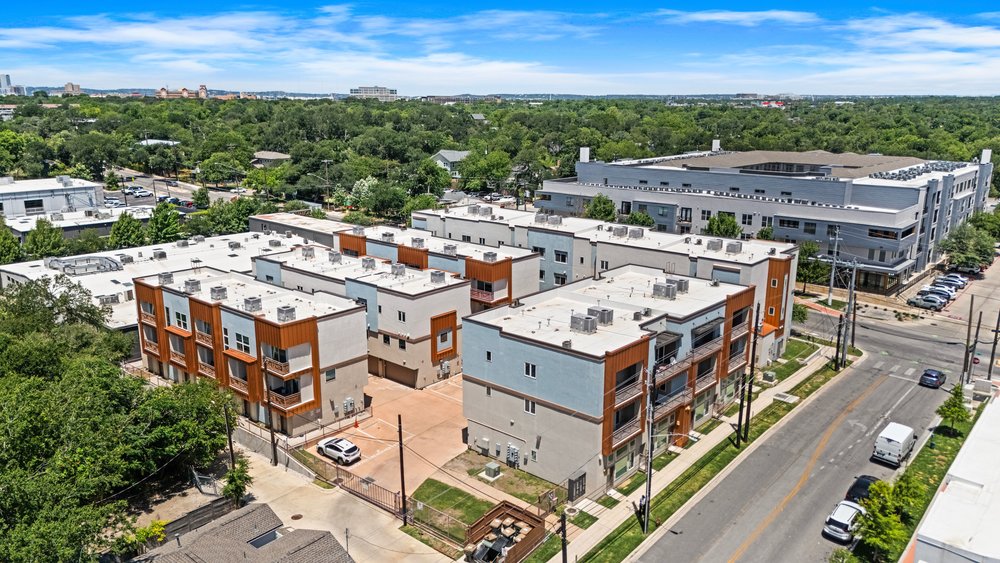 2827 Manor Road, Unit 2201 Austin, TX 78722 - Photo 40 of 40 Modern multi-level townhome-style residences featuring contemporary architecture with white and orange-brown siding, private balconies, and attached garages