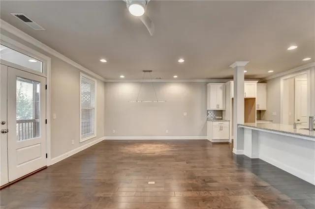 an empty room with wooden floor chandelier fan and windows