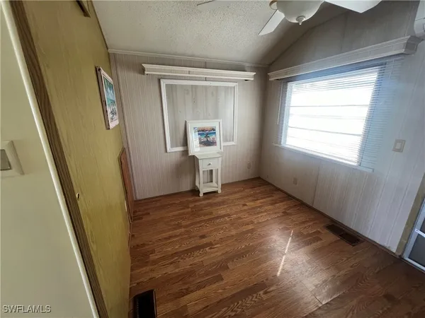 a view of empty room with wooden floor and fan